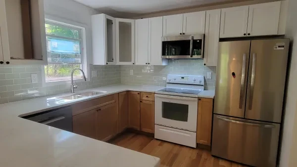 Kitchen with white and wood cabinets and sage backsplash