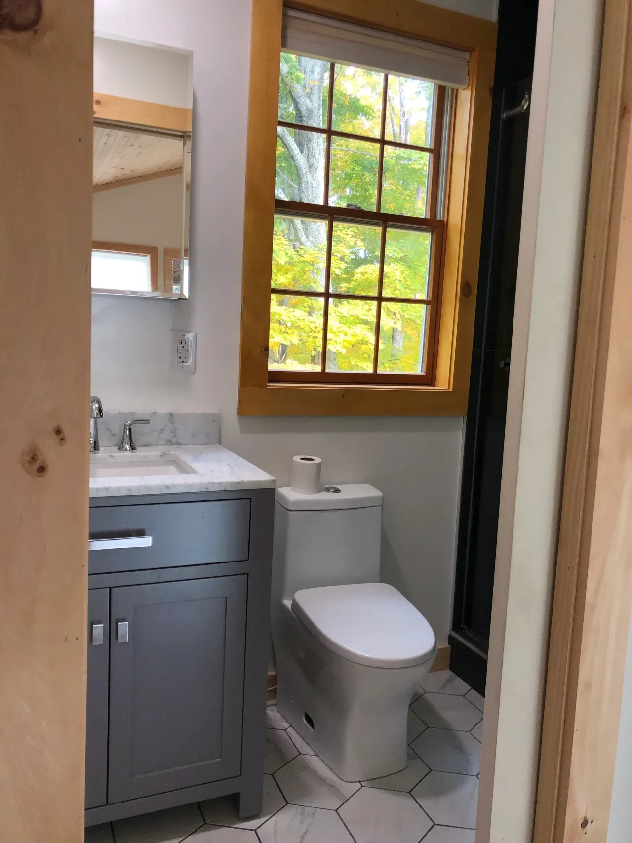 Finished bathroom with grey vanity, marble countertop and wood-framed window