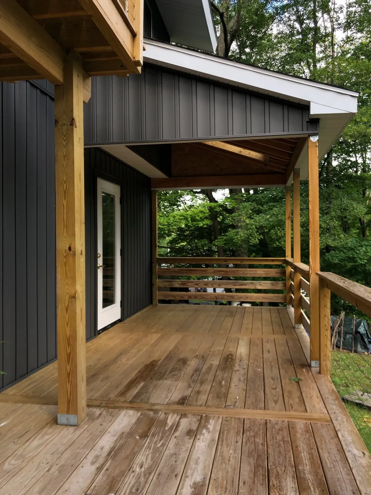 Finished covered porch with dark siding and wood deck