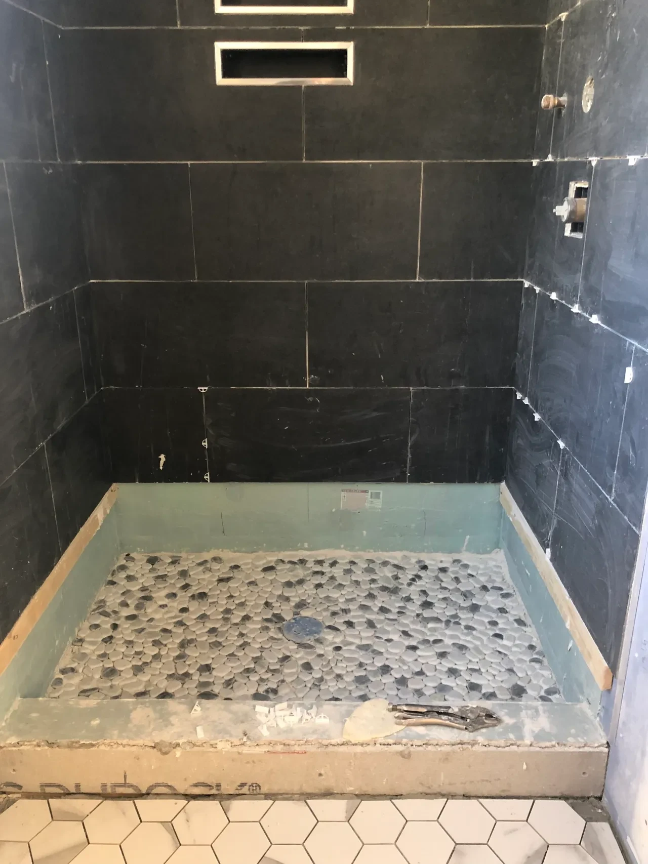 Pebble tile shower floor being installed in new bathroom