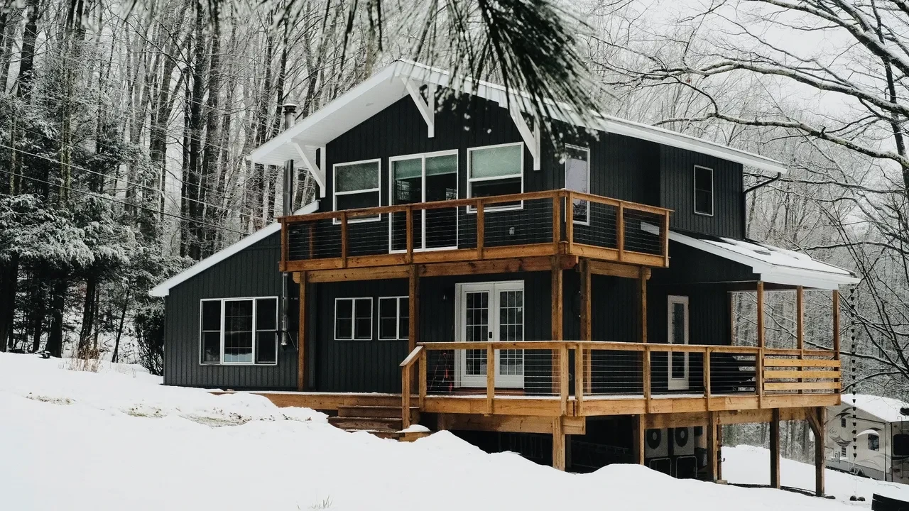 Completed modern black cabin exterior with wood decks in winter